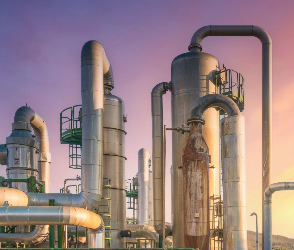 Industrial pipeline and refinery facility at sunset